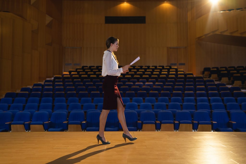 Businesswoman practicing and learning script while walking in the auditorium